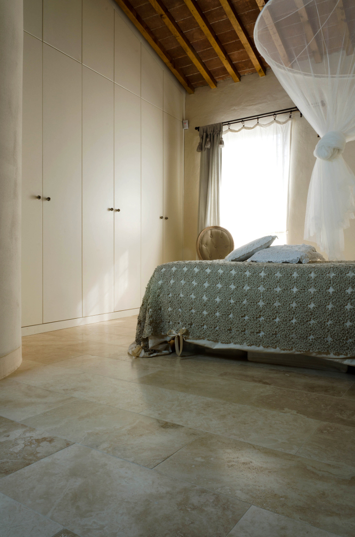 Camera da letto con pavimento in travertino chiaro